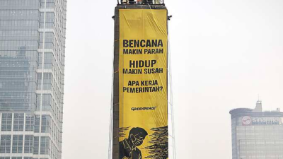 Greenpeace Indonesia membentangkan dua spanduk raksasa dari atas Patung Selamat Datang