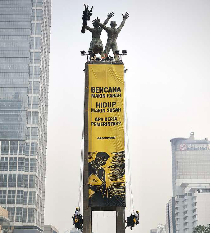 Greenpeace Indonesia membentangkan dua spanduk raksasa dari atas Patung Selamat Datang